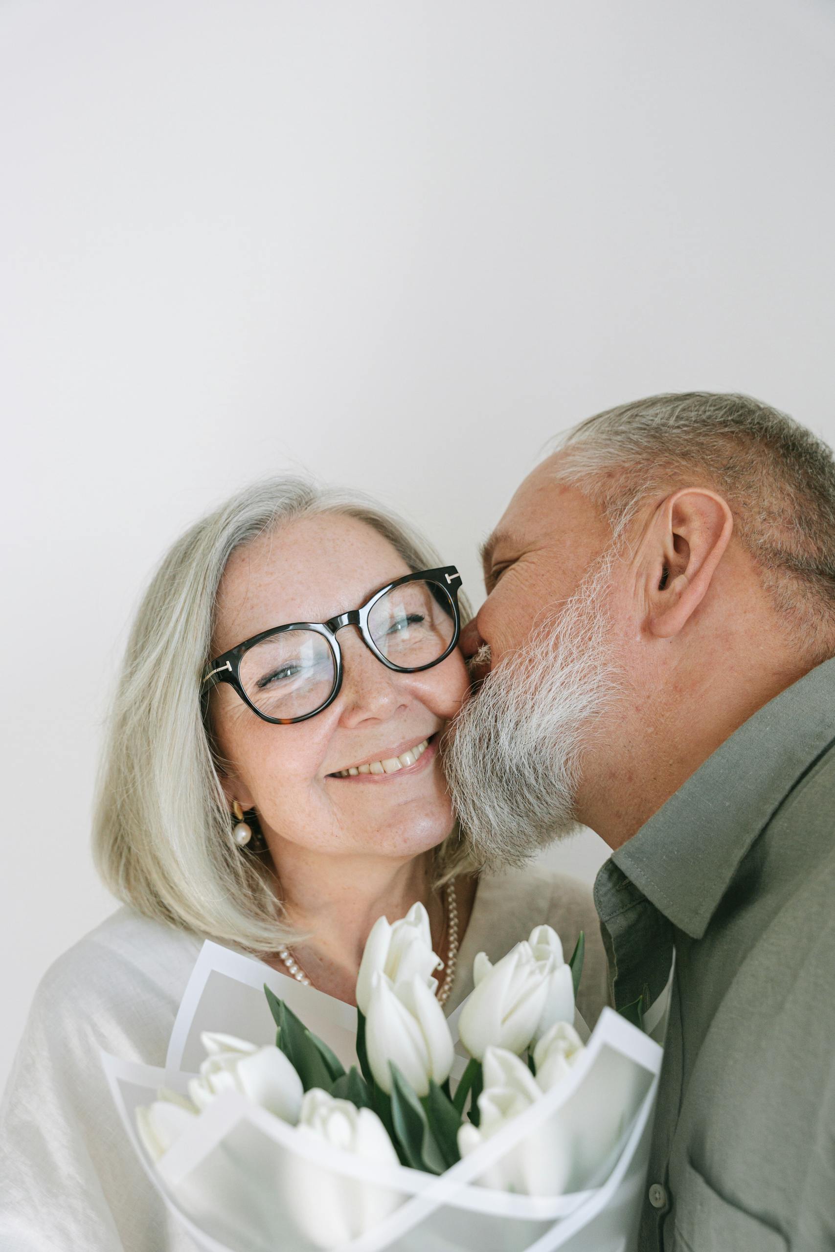 A loving elderly couple shares a joyful moment with a bouquet of tulips.