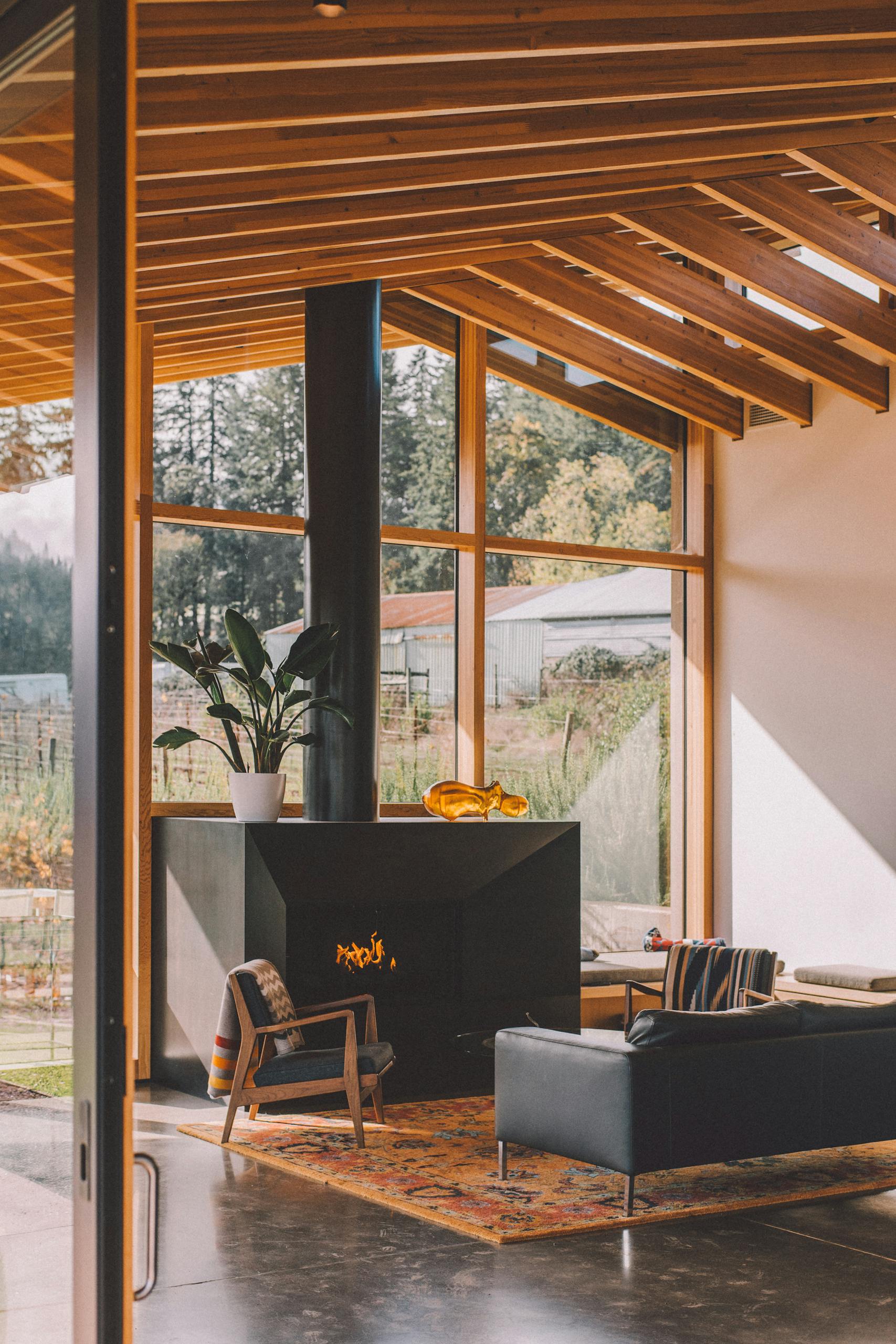Contemporary room interior with leather couch and fireplace near glass wall in countryside house