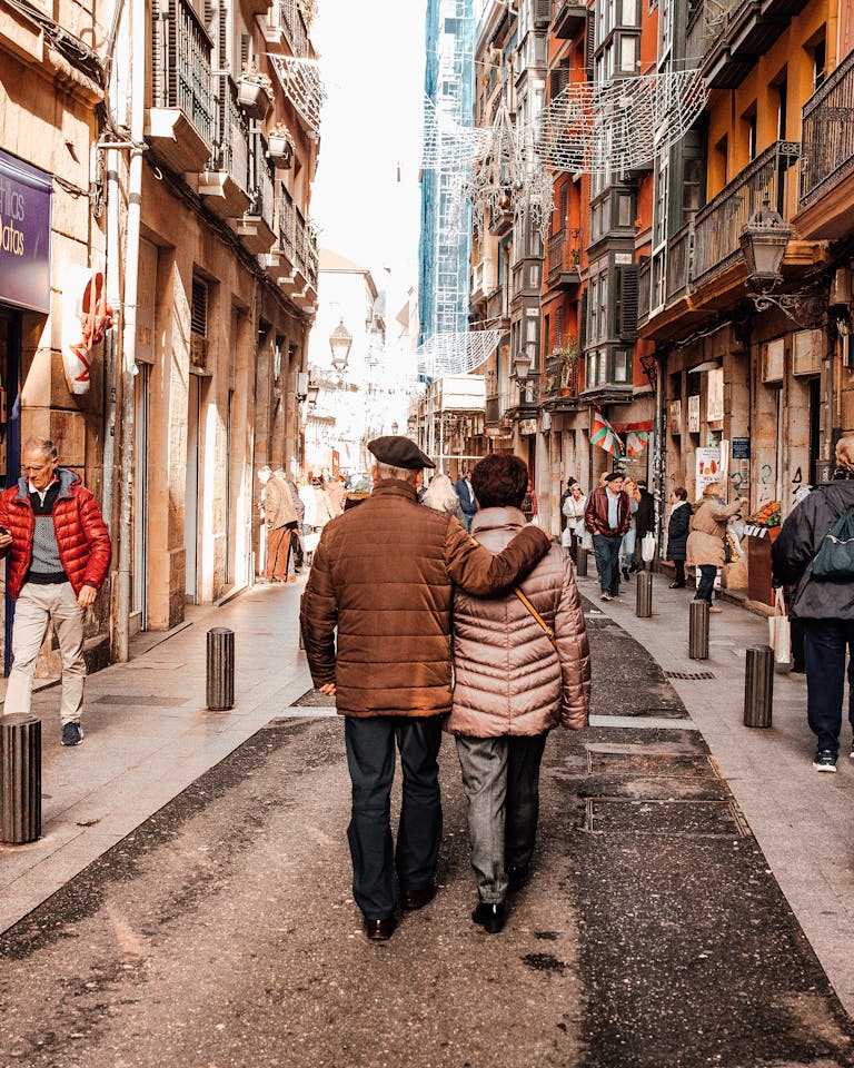 Senior couple enjoying a walk in the bustling streets of Bilbao, Spain on a sunny day.