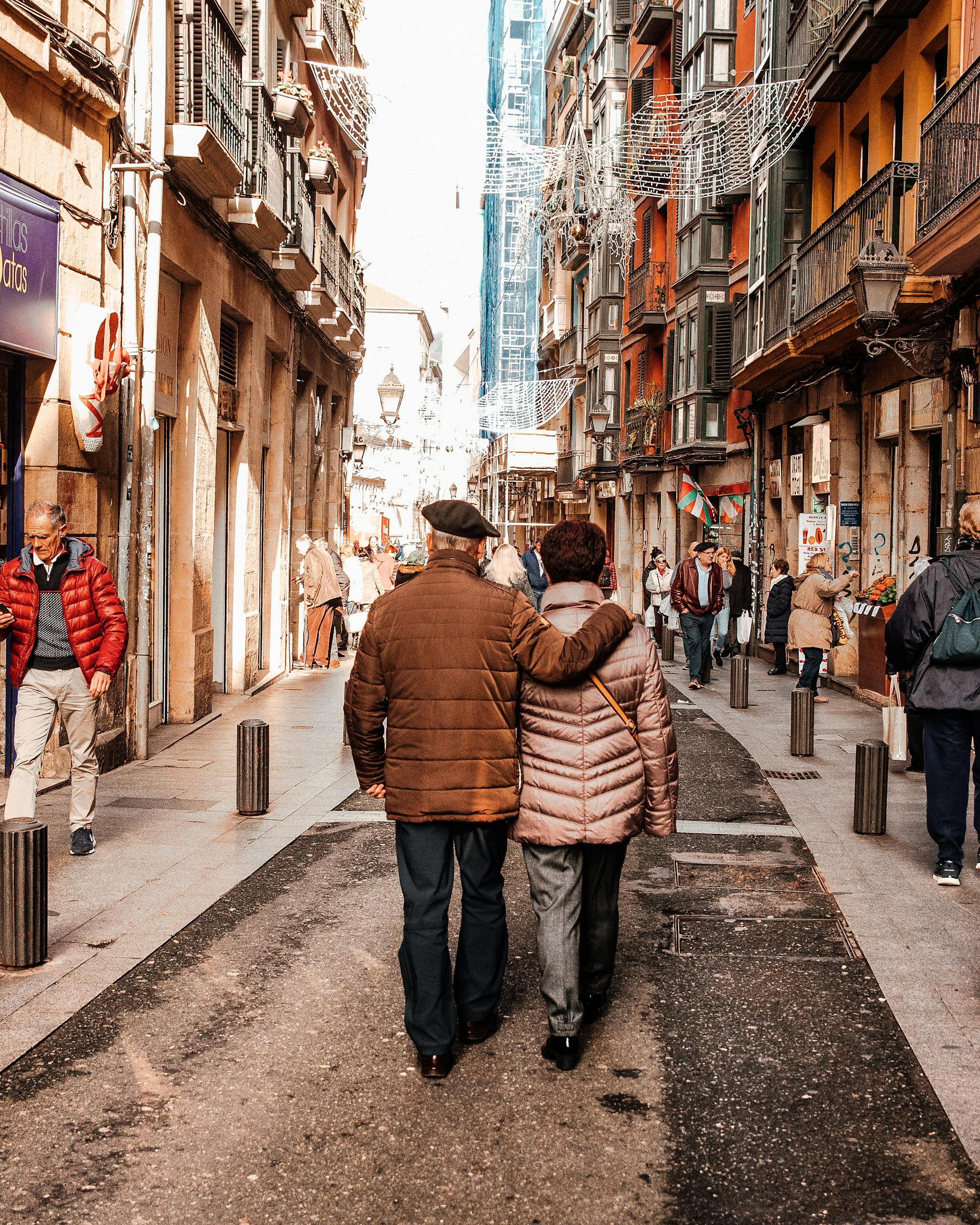 Senior couple enjoying a walk in the bustling streets of Bilbao, Spain on a sunny day.
