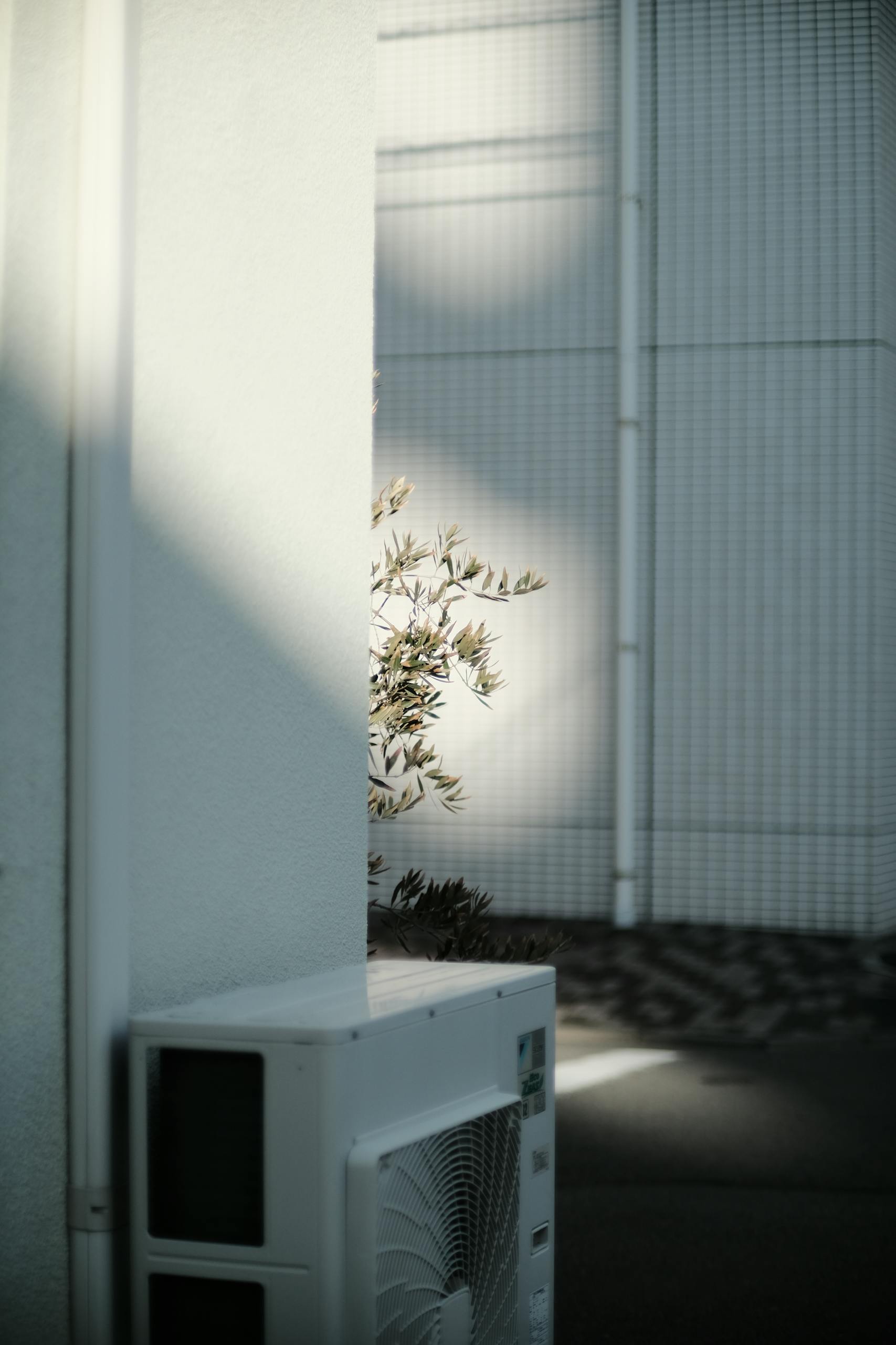 A contemporary air conditioning unit installed on a white corner wall of a modern urban building.