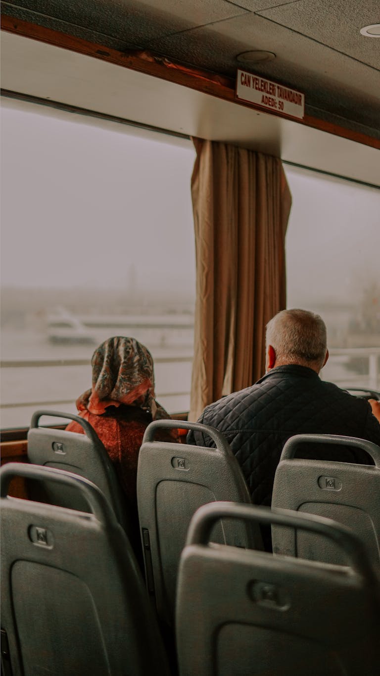 A couple sits quietly in a bus overlooking a foggy landscape, creating a serene atmosphere.