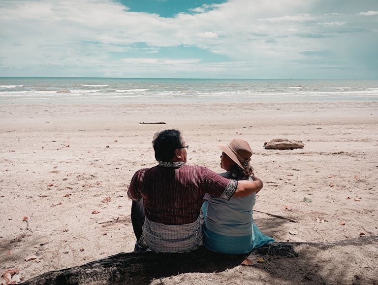 A couple sitting on the beach, enjoying the serene ocean view together.