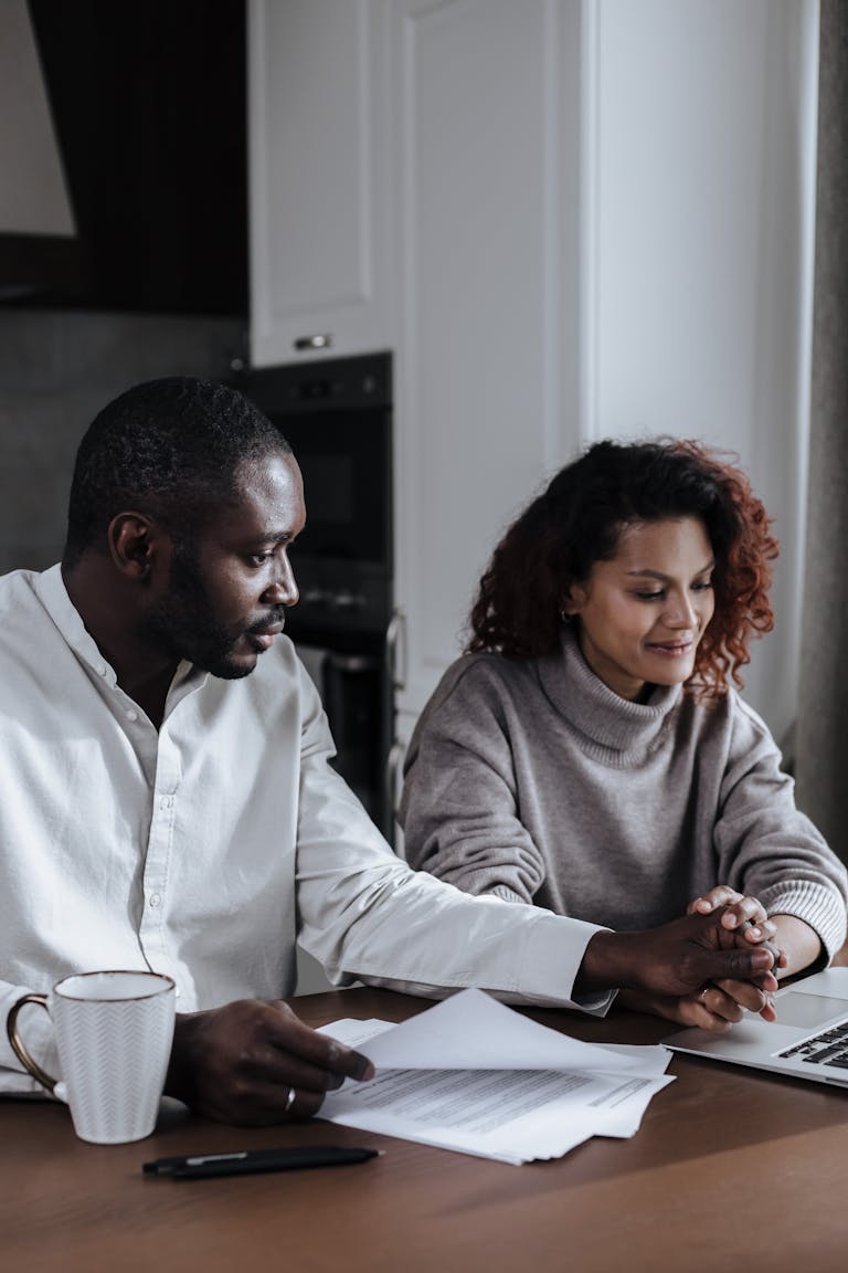 A couple working together at home, reviewing documents on a laptop.