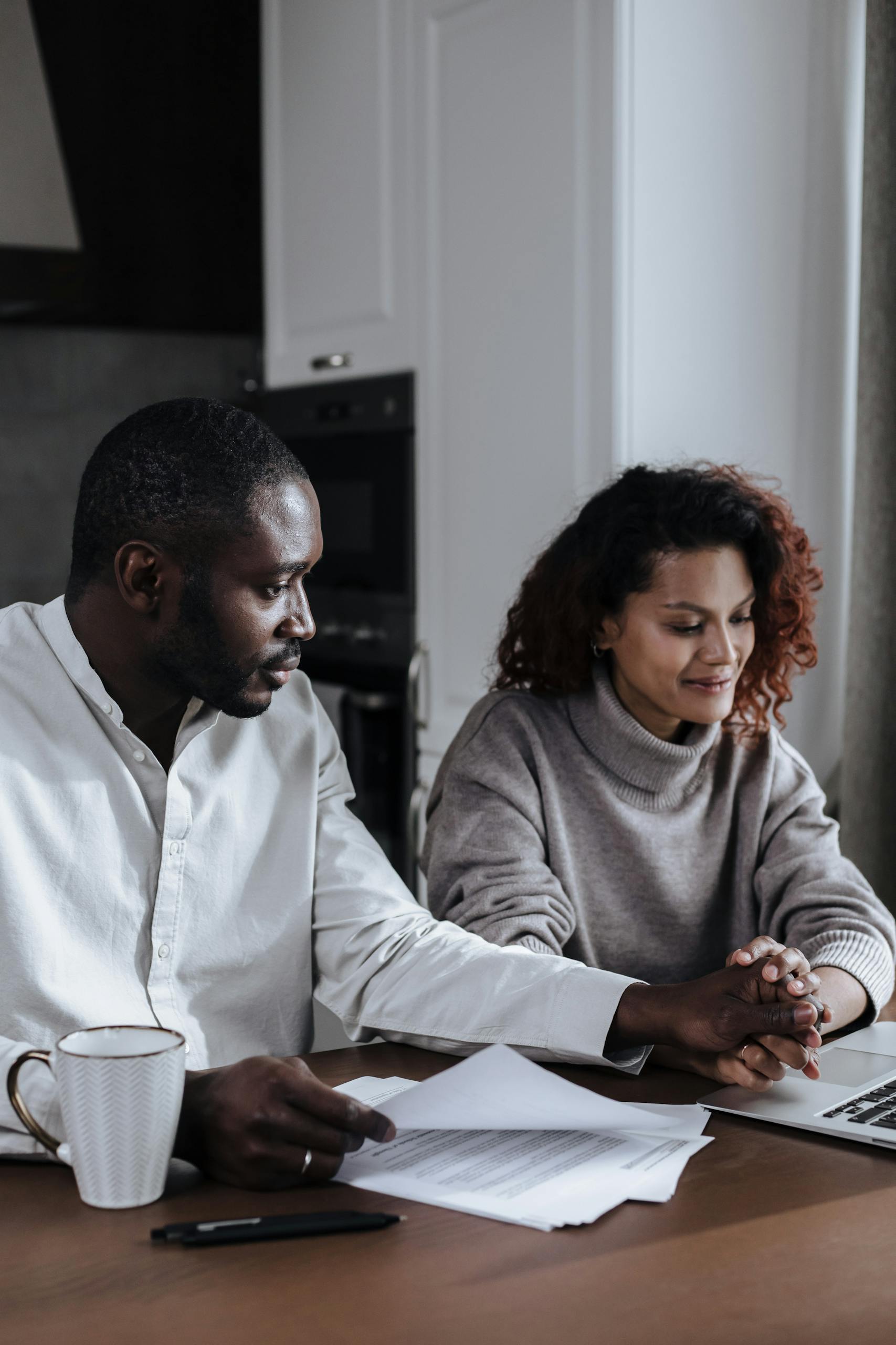A couple working together at home, reviewing documents on a laptop.