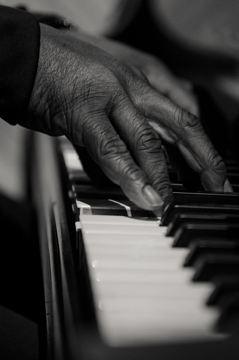 A detailed close-up shot of fingers playing piano keys, captured in artistic black and white.