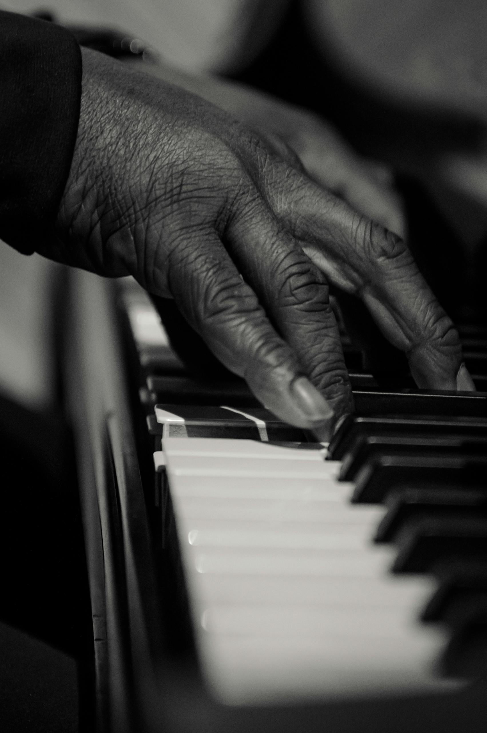 A detailed close-up shot of fingers playing piano keys, captured in artistic black and white.