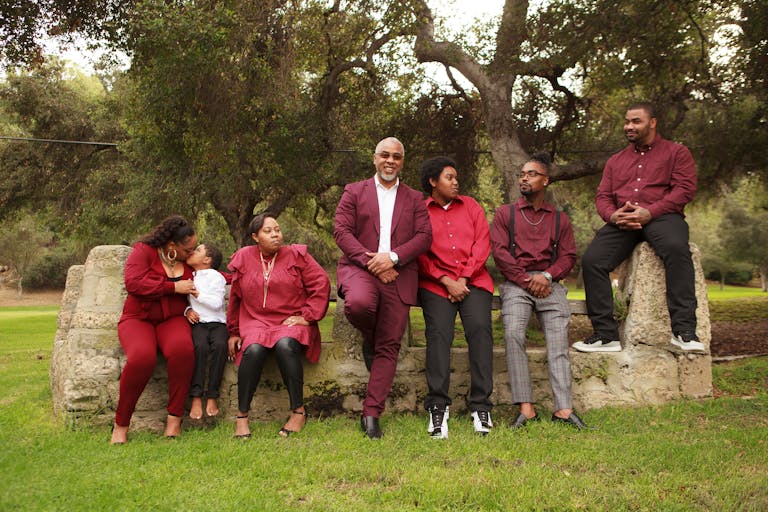 A family gathered in a park wearing coordinated outfits, posing on a stone wall.