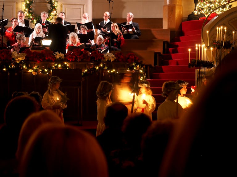 A festive candlelight ceremony with a choir performing at a Seattle church with holiday decorations.