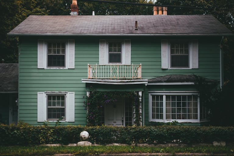A picturesque green wooden house with a charming facade and lush surroundings, perfect for a peaceful home setting.