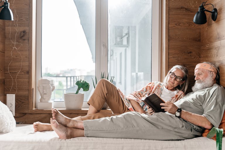 A senior couple enjoying a peaceful moment reading together indoors, exemplifying love and relaxation.