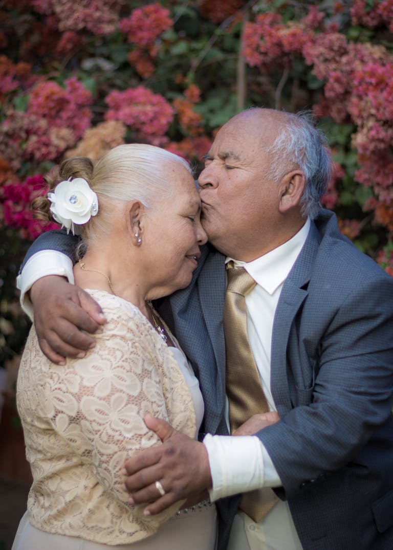 A senior couple shares a tender hug amidst vibrant floral background.