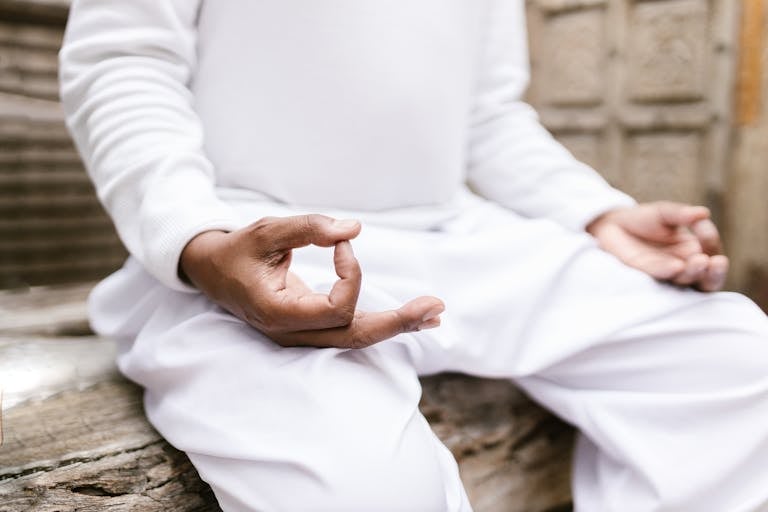 A serene person meditating outdoors in white clothing, focusing on mindfulness and spiritual balance.