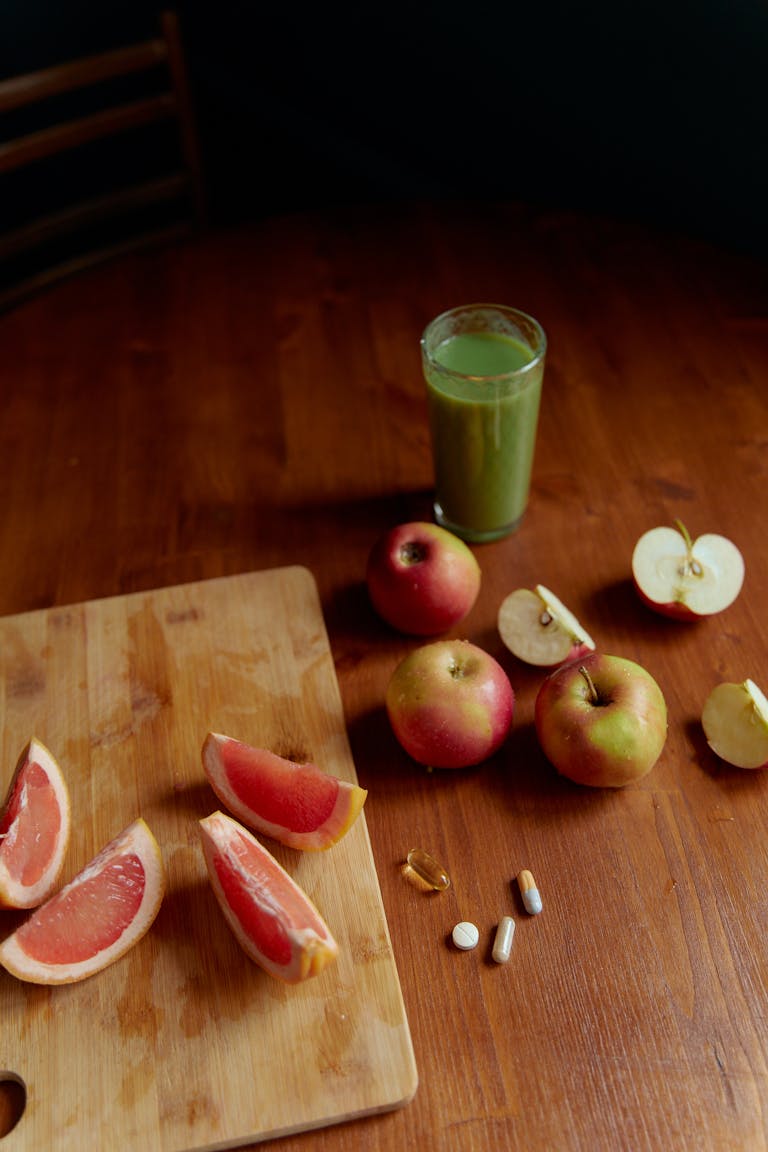 A vibrant display of fresh fruits, grapefruit, apples, and a glass of green juice, symbolizing health.