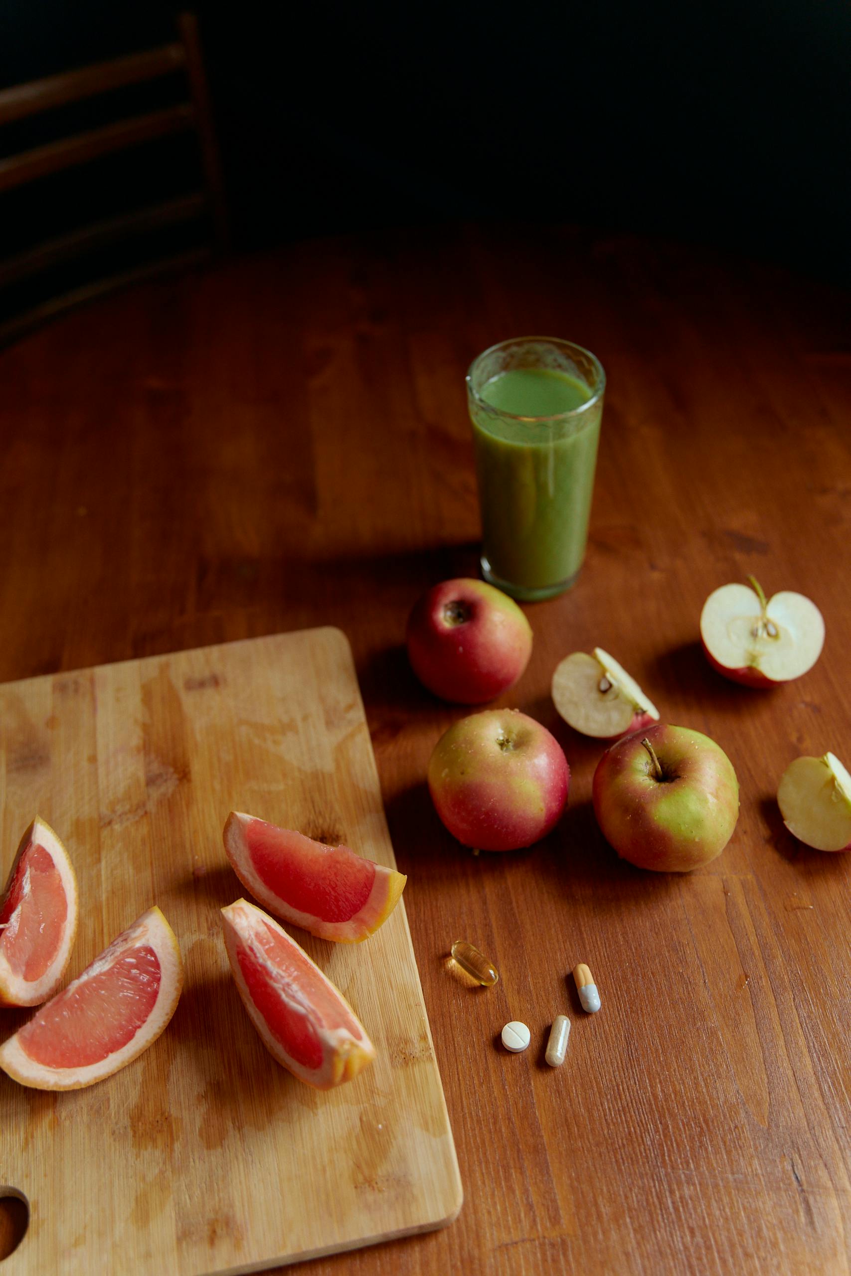 A vibrant display of fresh fruits, grapefruit, apples, and a glass of green juice, symbolizing health.