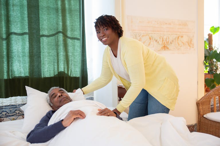 A woman tending to an elderly man in a bright and warm bedroom, symbolizing care and family support.
