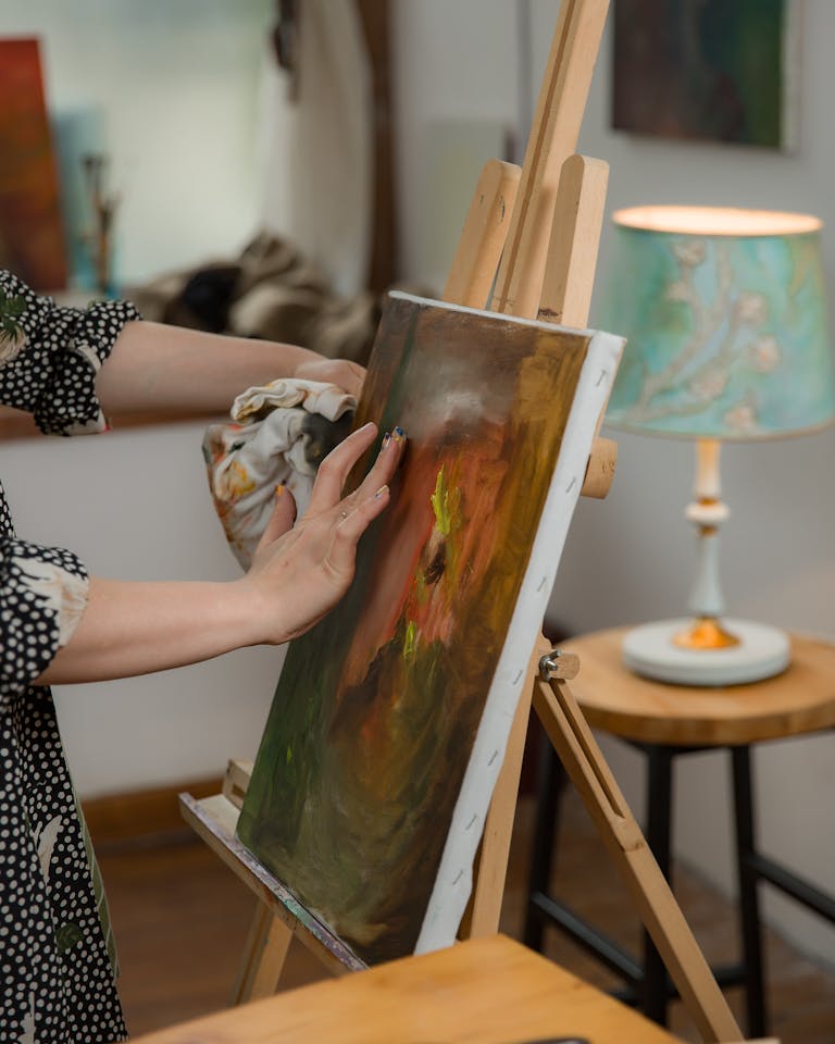 Artist working on a colorful painting in a cozy indoor studio, showcasing creativity and handmade art.