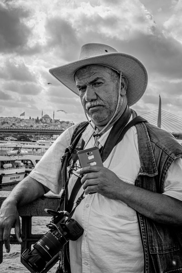 Black and white portrait of a man with a camera on a bridge, capturing the essence of travel.