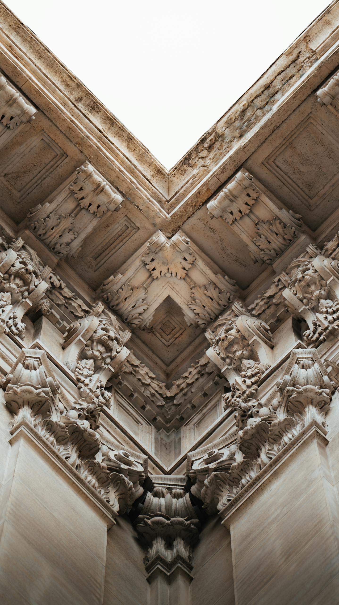 Close-up view of intricate stone carvings in a neo-classical style at an architectural corner.