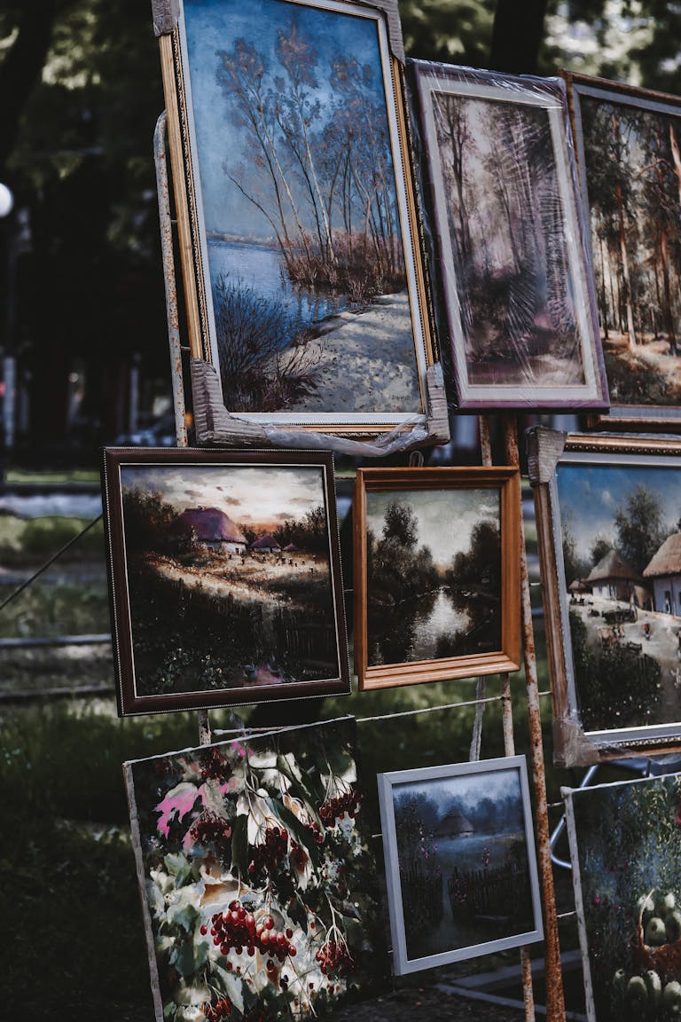 Display of framed paintings in an outdoor setting capturing natural landscapes.