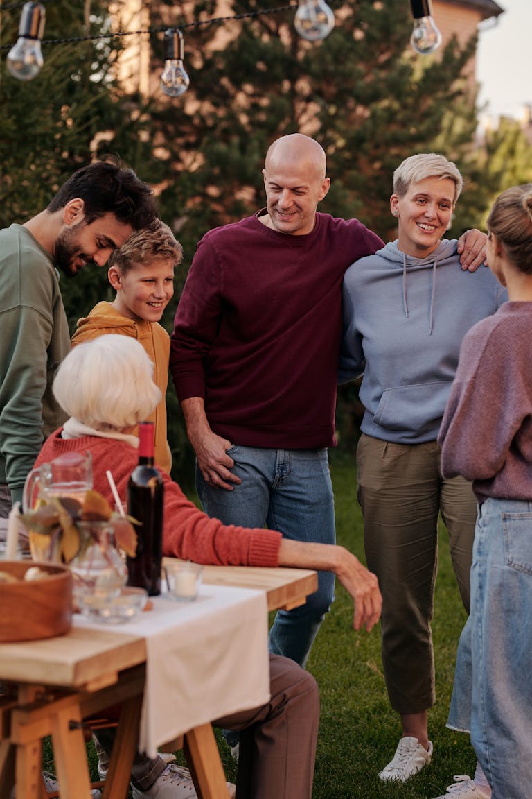 Happy family members talking and laughing while having picnic on backyard in sunny day