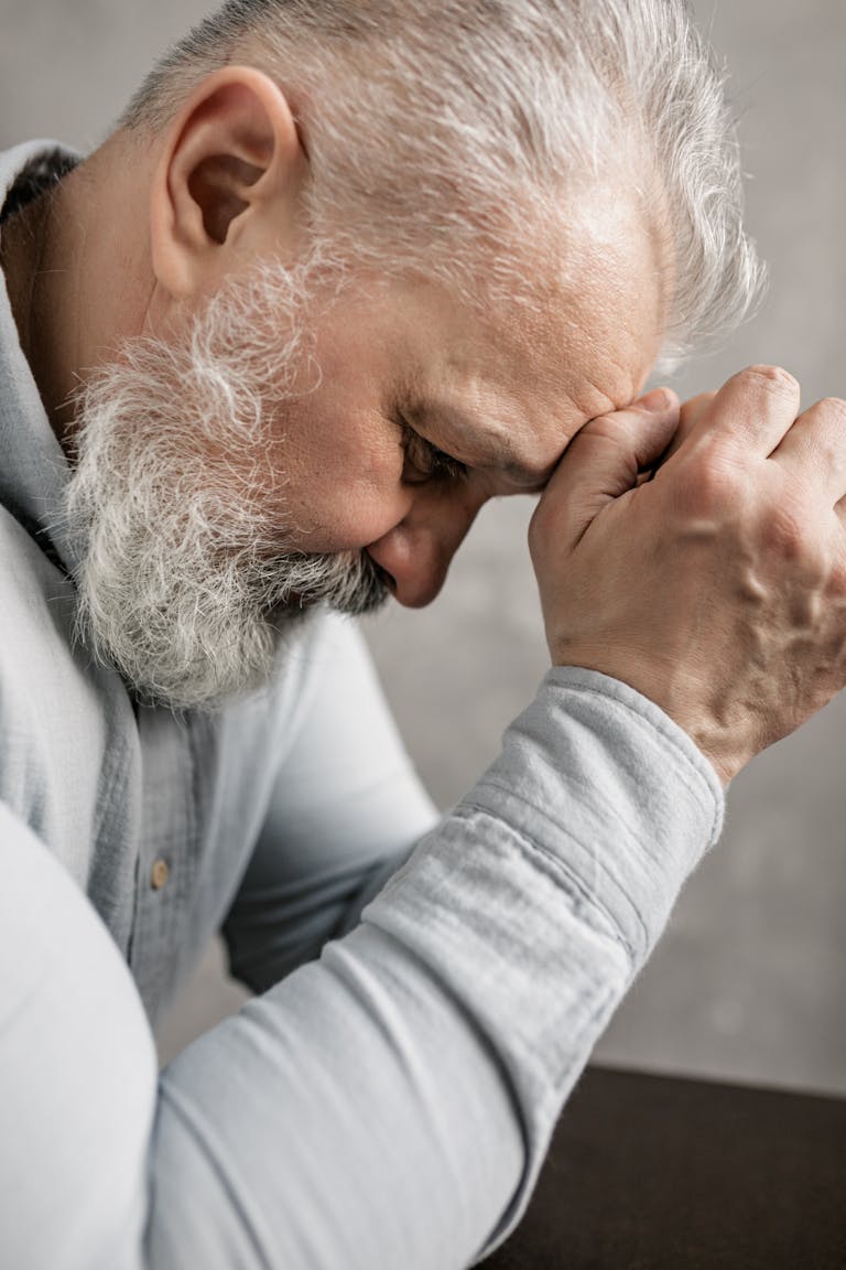 Profile view of a thoughtful elderly man with gray hair and beard, deep in contemplation.