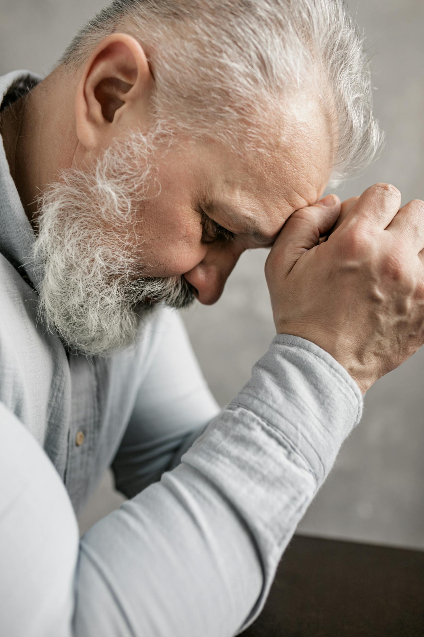 Profile view of a thoughtful elderly man with gray hair and beard, deep in contemplation.