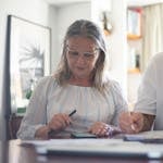 Senior couple calculating expenses at home office desk with documents and notes.