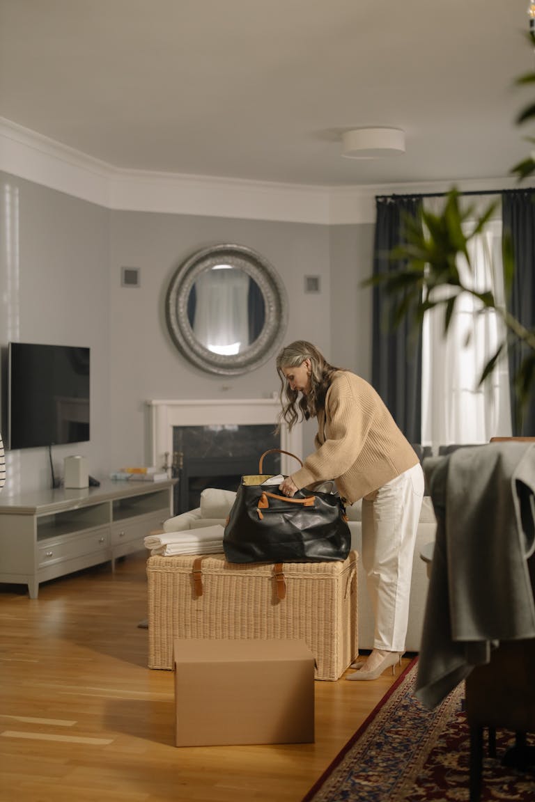 Senior woman packing a bag in a cozy living room, preparing for moving out.