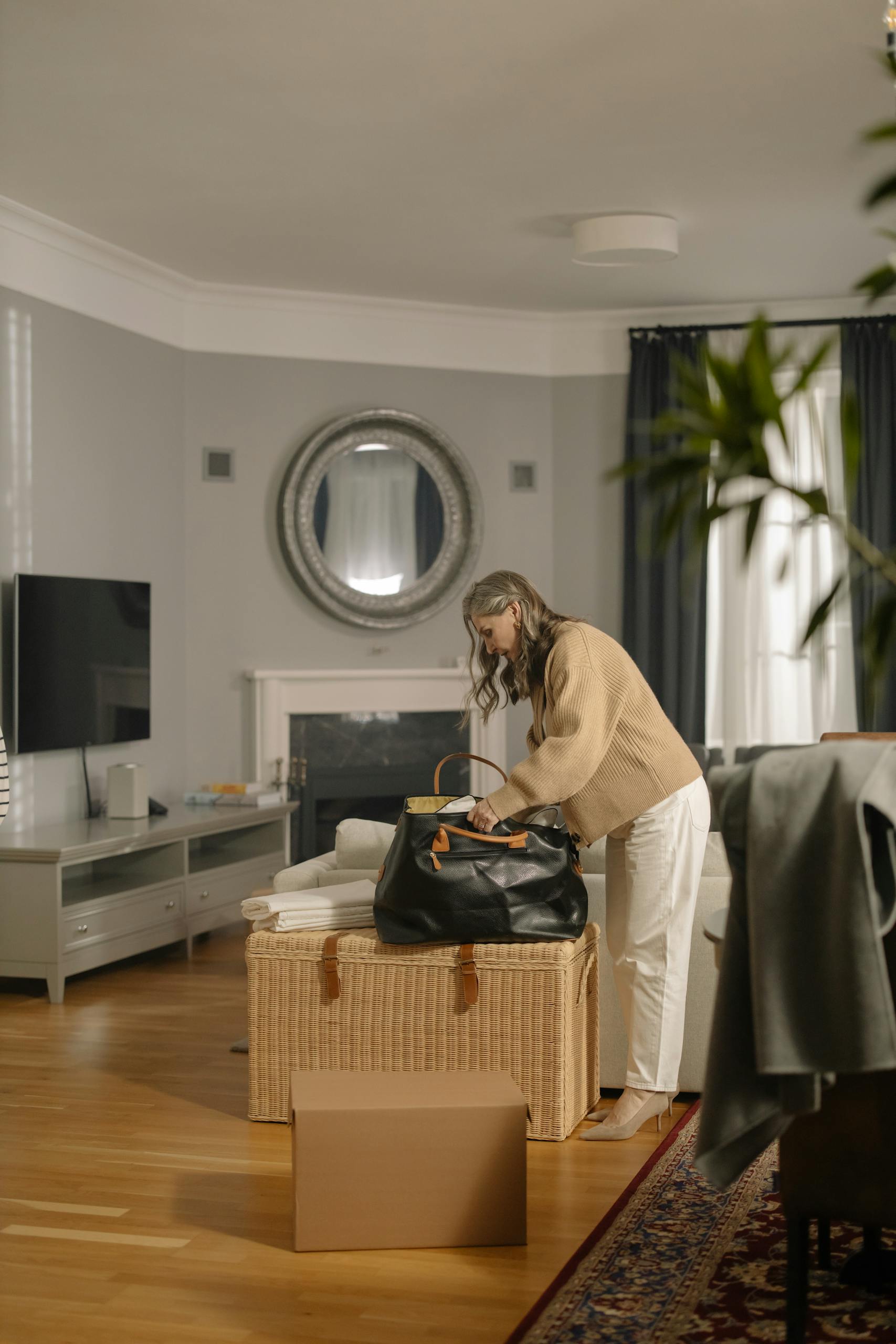 Senior woman packing a bag in a cozy living room, preparing for moving out.