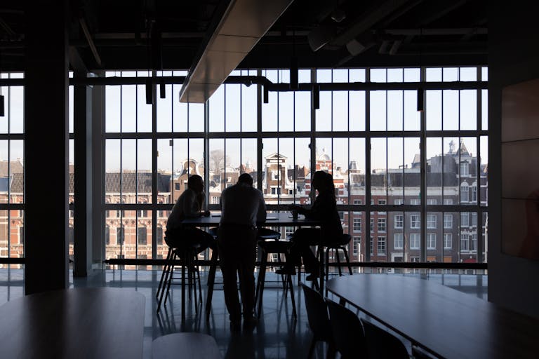Silhouette of a business meeting in an Amsterdam office with cityscape view.