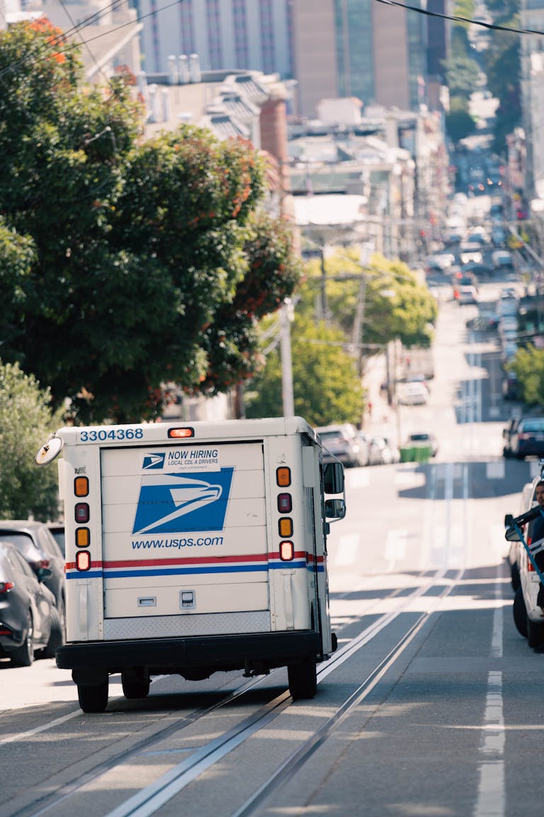 USPS truck driving down a busy urban street, capturing everyday city life.