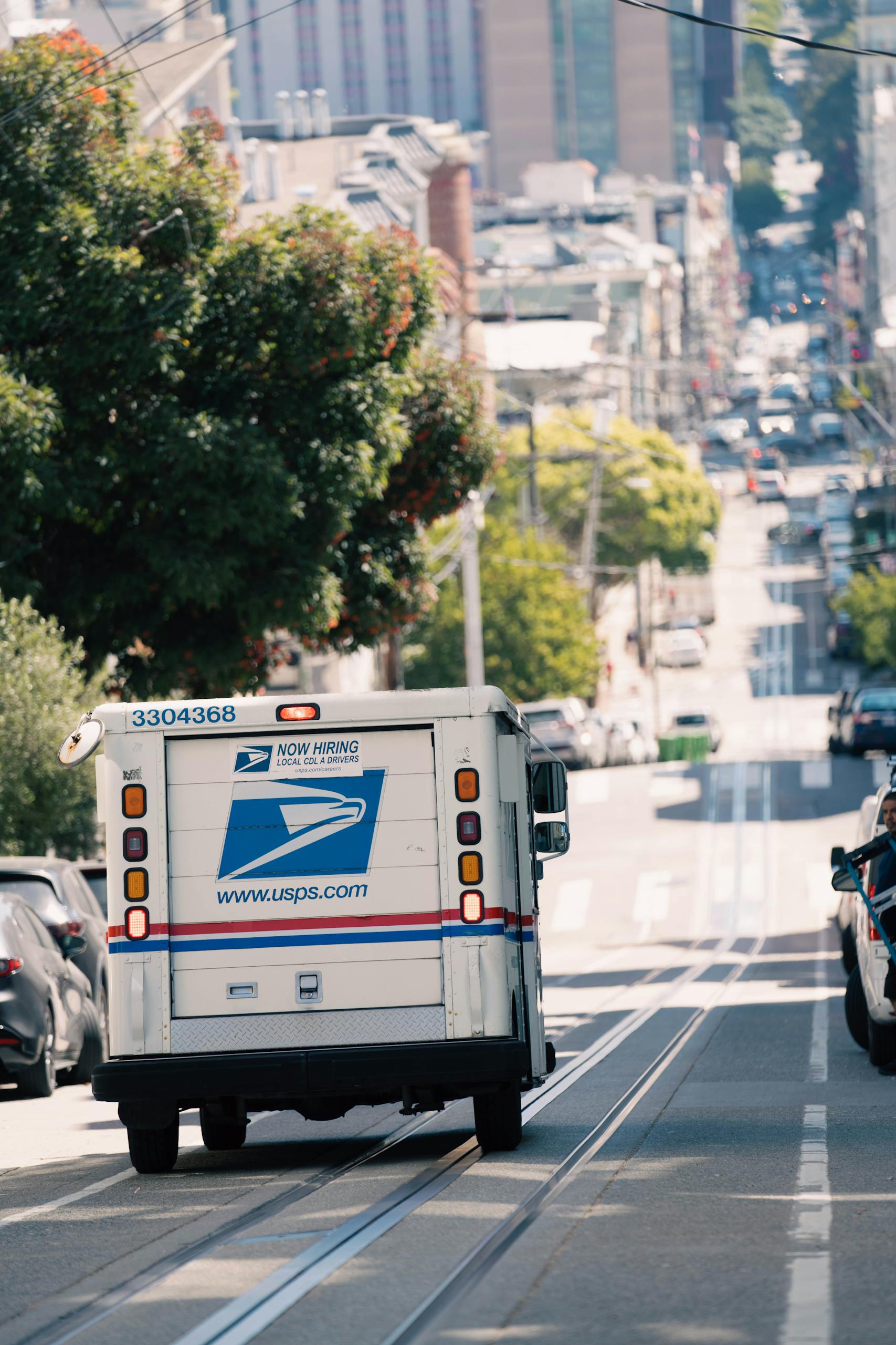 USPS truck driving down a busy urban street, capturing everyday city life.