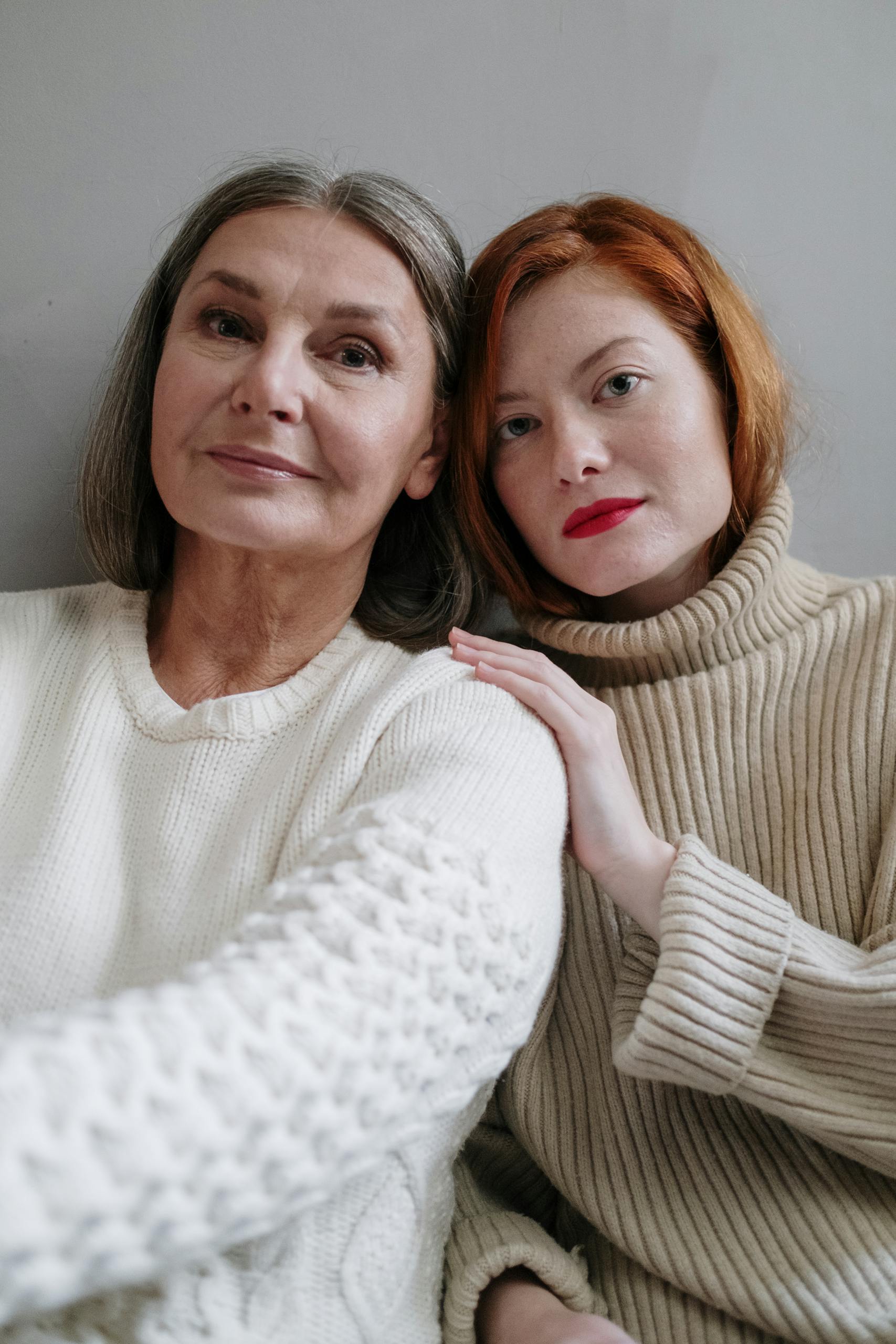 Warm and intimate portrait of a mother and daughter in cozy knitwear, sharing a tender moment.