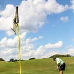 Elderly man golfing on a sunny day at Eustis golf course, captured during a putt.