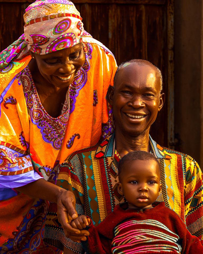Smiling family wearing vibrant traditional clothing, capturing a joyful moment.