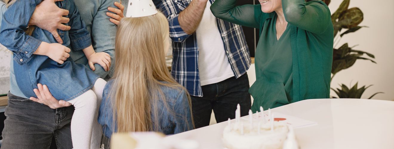 A joyful family birthday celebration with grandparents and children wearing party hats inside a cozy home.