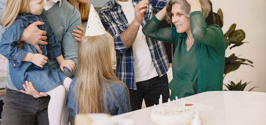 A joyful family birthday celebration with grandparents and children wearing party hats inside a cozy home.