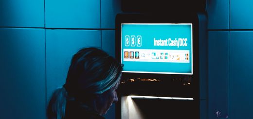 A woman uses an ATM at night in Istanbul under moody blue lighting.