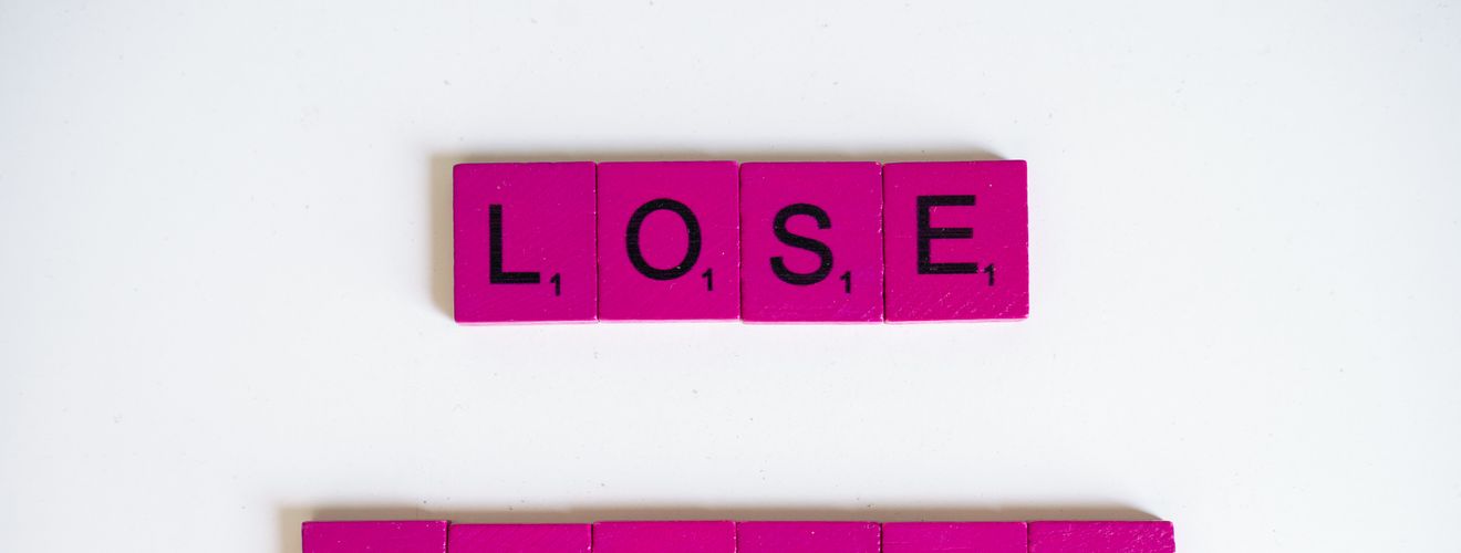 Creative image of the phrase 'Lose Weight' spelled with Scrabble tiles on a white background.