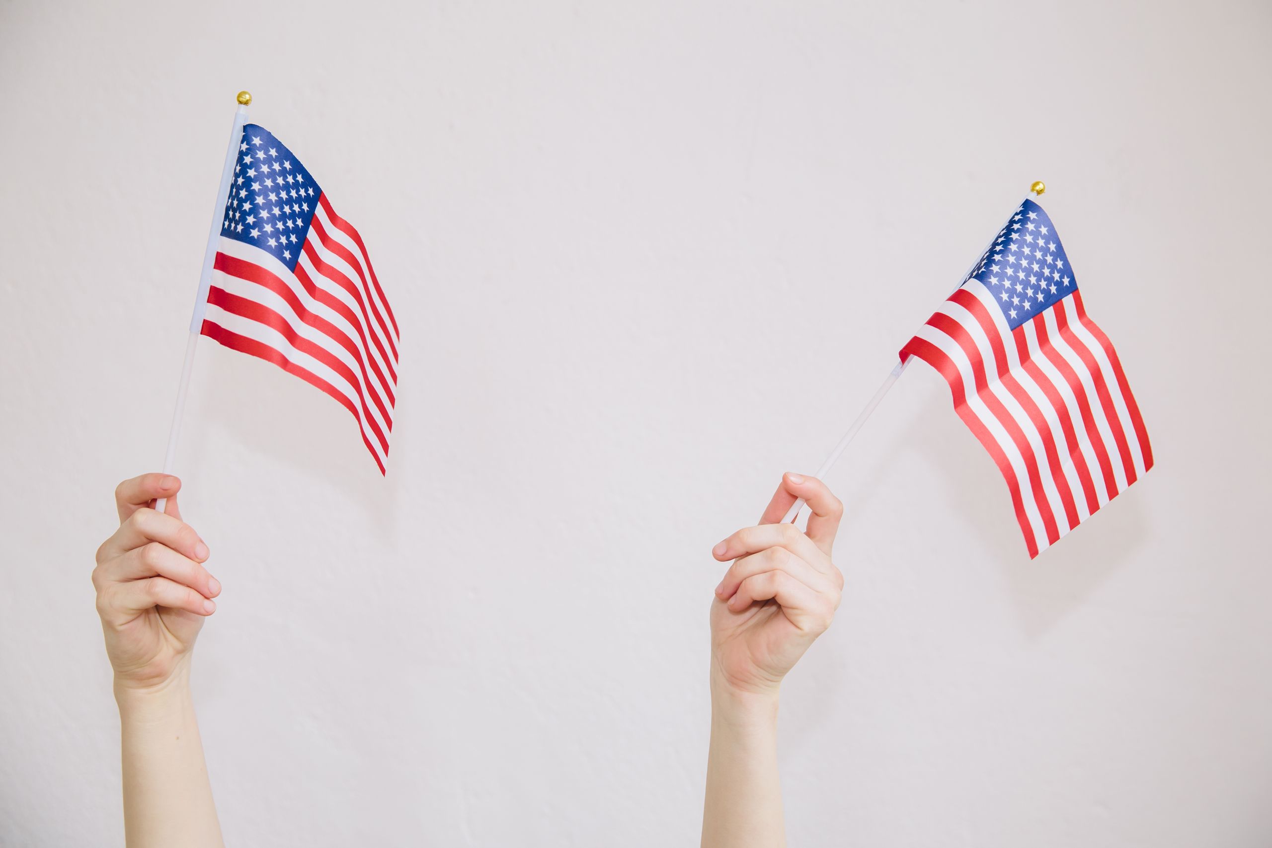 Crop anonymous female showing United States flags against white background illustrating national emblem with stars and stripes