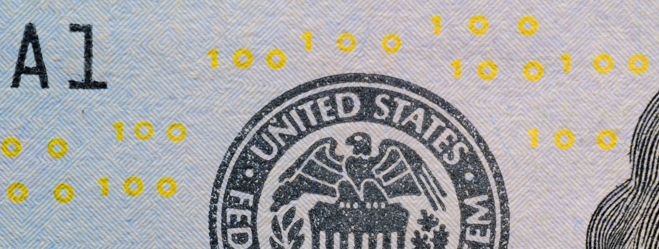 Detailed view of the US Federal Reserve System seal on currency with yellow digital numbers.