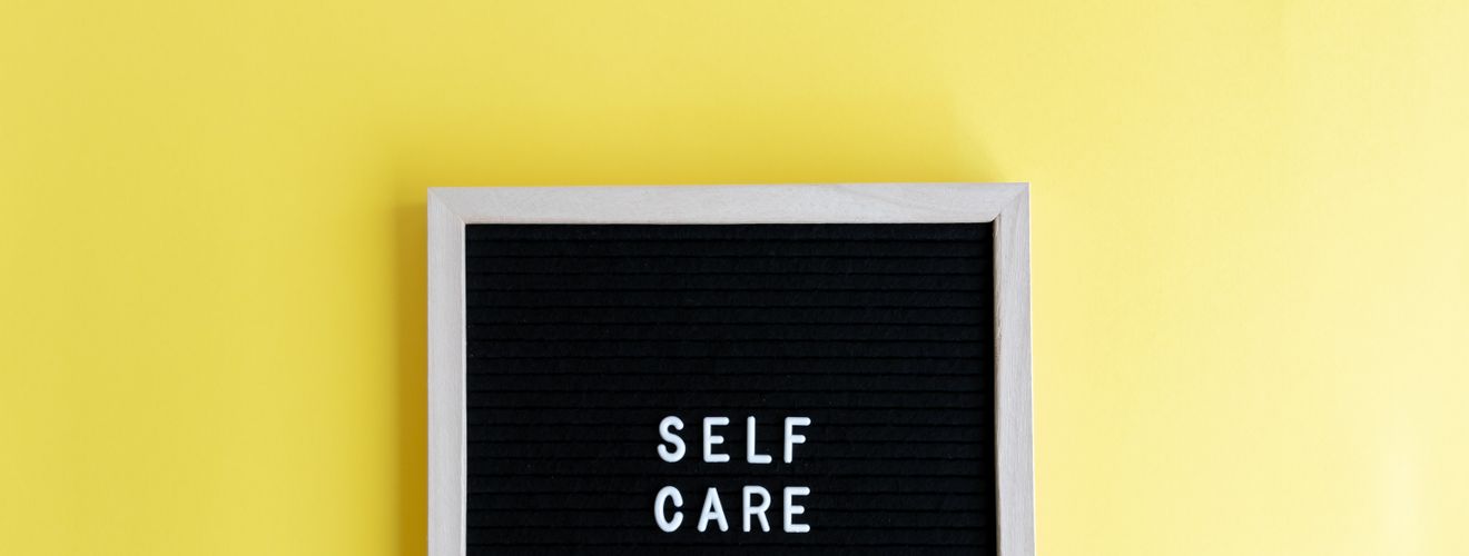 Inspiring self care message on a blackboard with a vibrant yellow background.