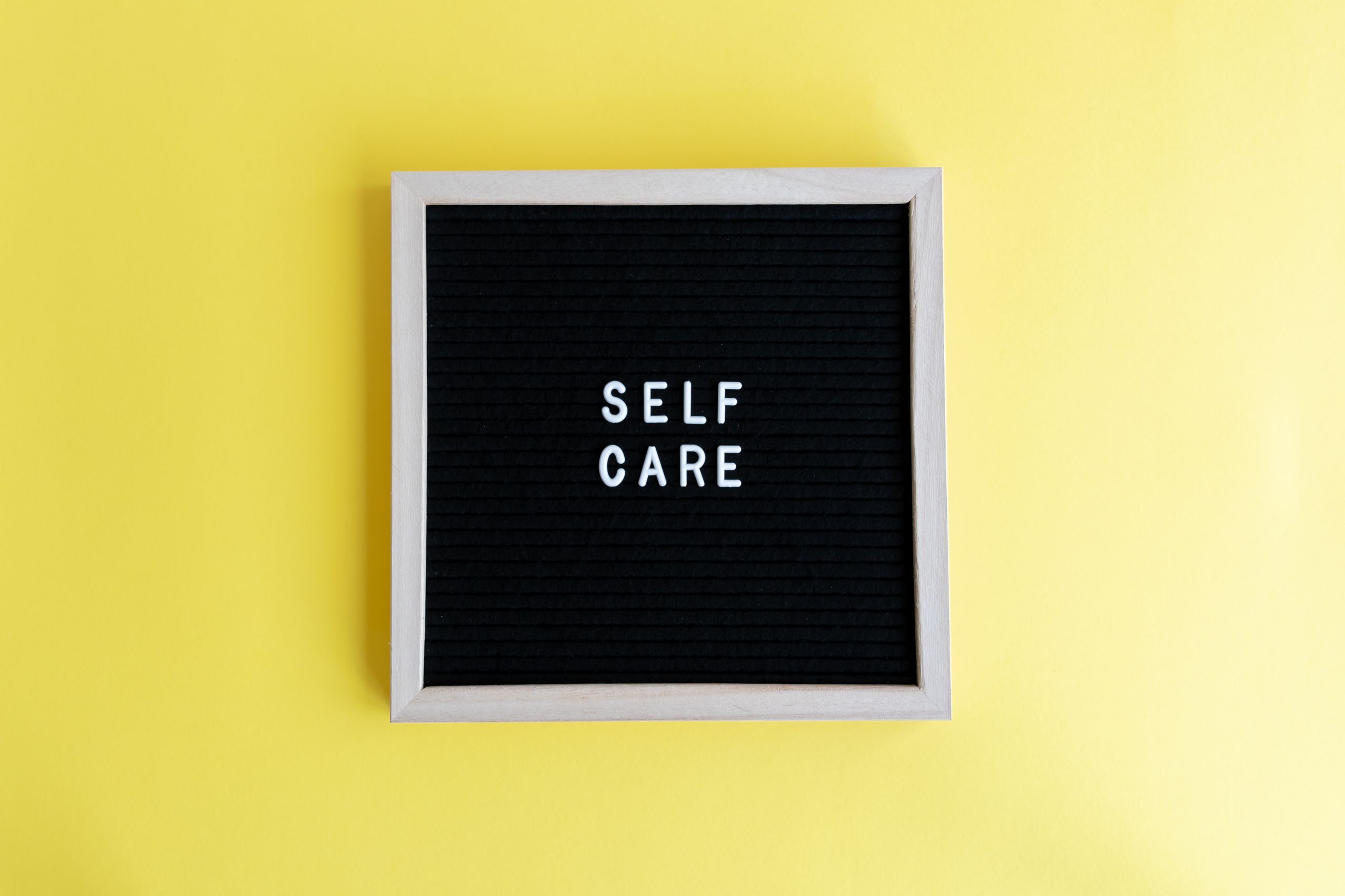 Inspiring self care message on a blackboard with a vibrant yellow background.
