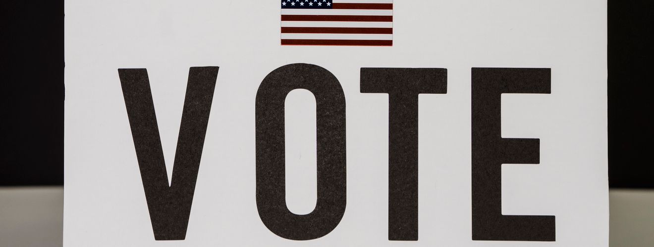 A person placing a ballot into a voting box, symbolizing democratic participation and civic duty.