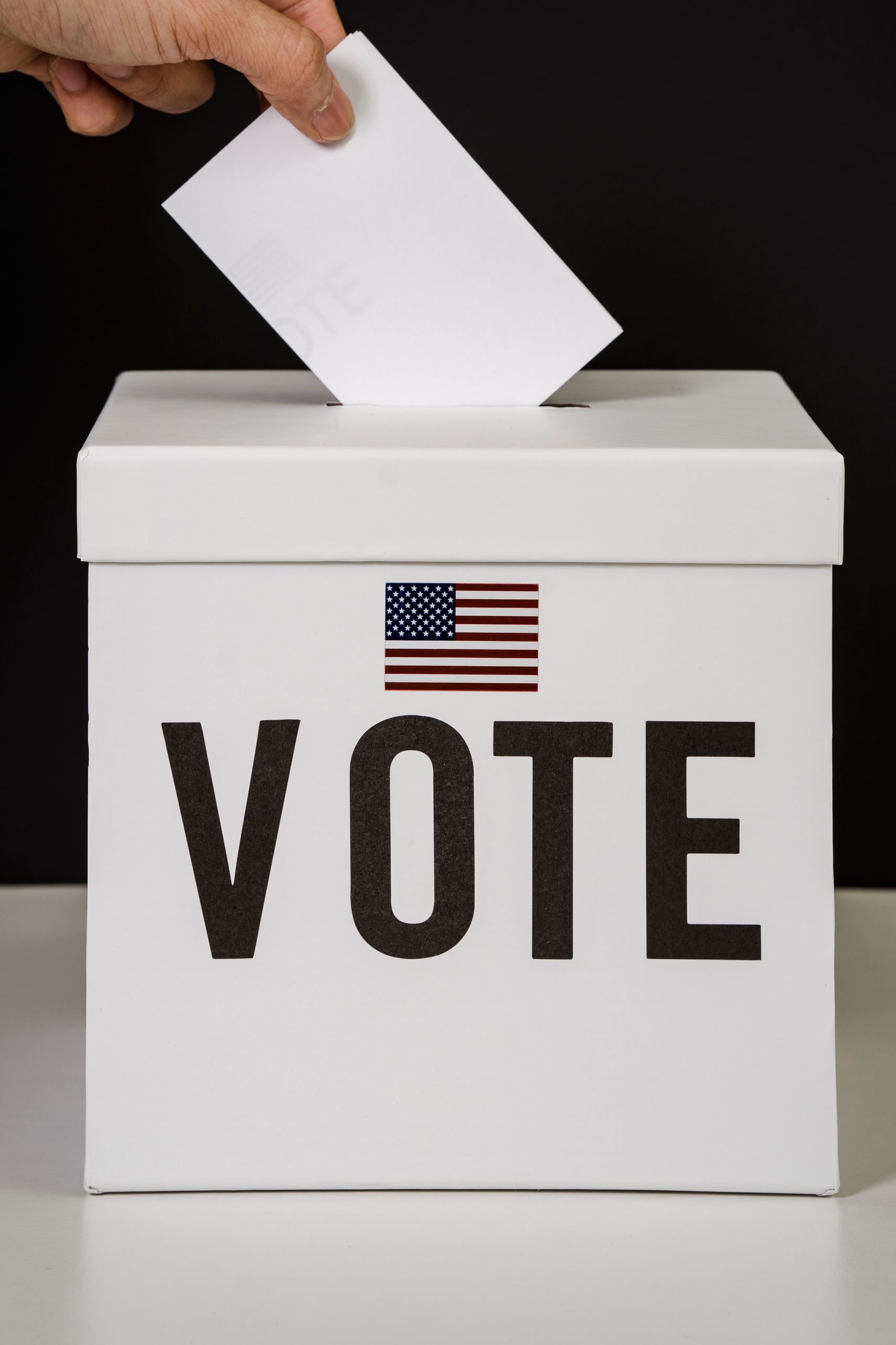 A person placing a ballot into a voting box, symbolizing democratic participation and civic duty.