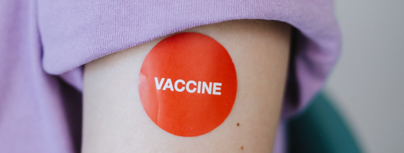 A person's arm with a red vaccine sticker, symbolizing vaccination.