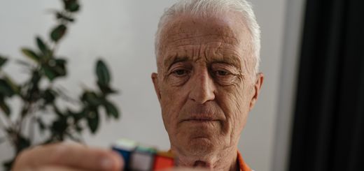 Elderly man concentrating on solving a Rubik's Cube, showcasing focus and mental agility.