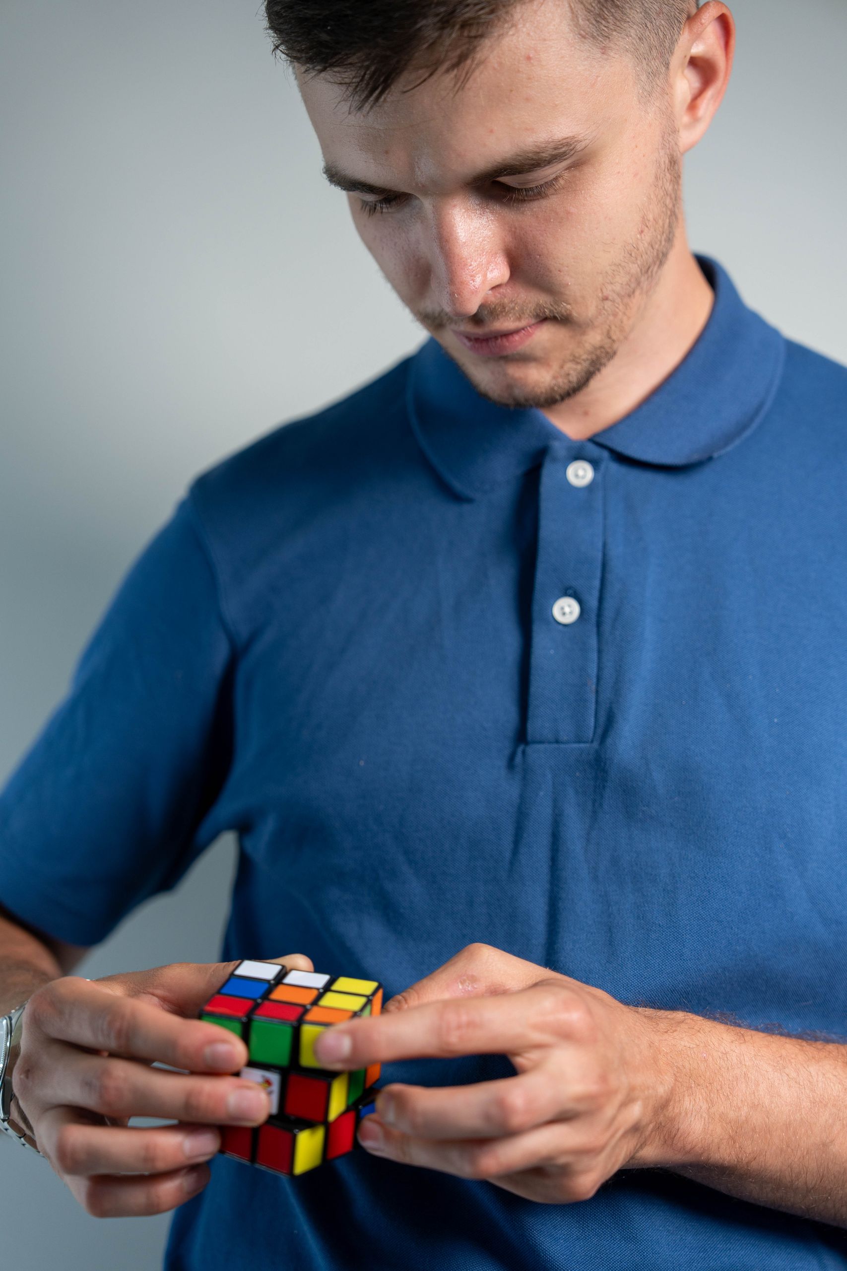 Focused young adult solving a Rubik's Cube challenge indoors.