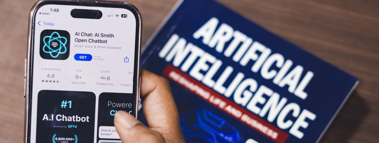 Smartphone displaying AI app with book on AI technology in background.